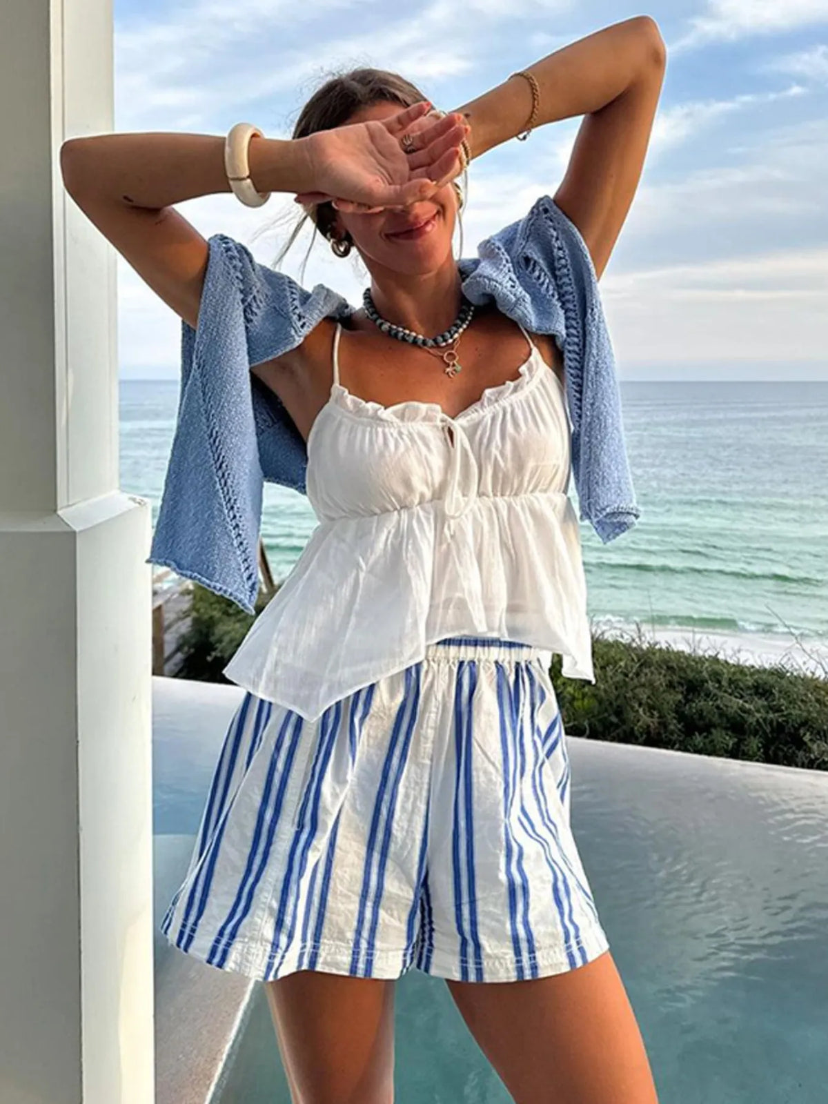 Woman wearing white and blue striped shorts by the ocean
