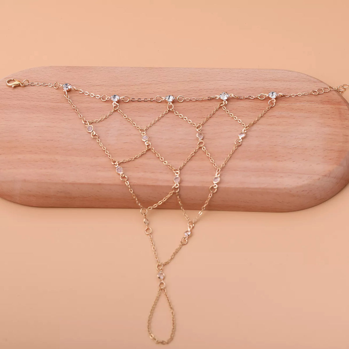 Close view of the gold-tone hand chain laid across a wooden display