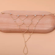 Close view of the gold-tone hand chain laid across a wooden display
