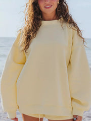 Front view of a pale yellow oversized sweatshirt and matching shorts at the beach.