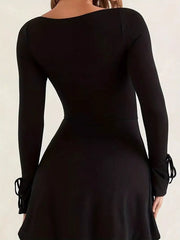 Back view of the black fitted mini dress with long sleeves and tied flared cuffs.