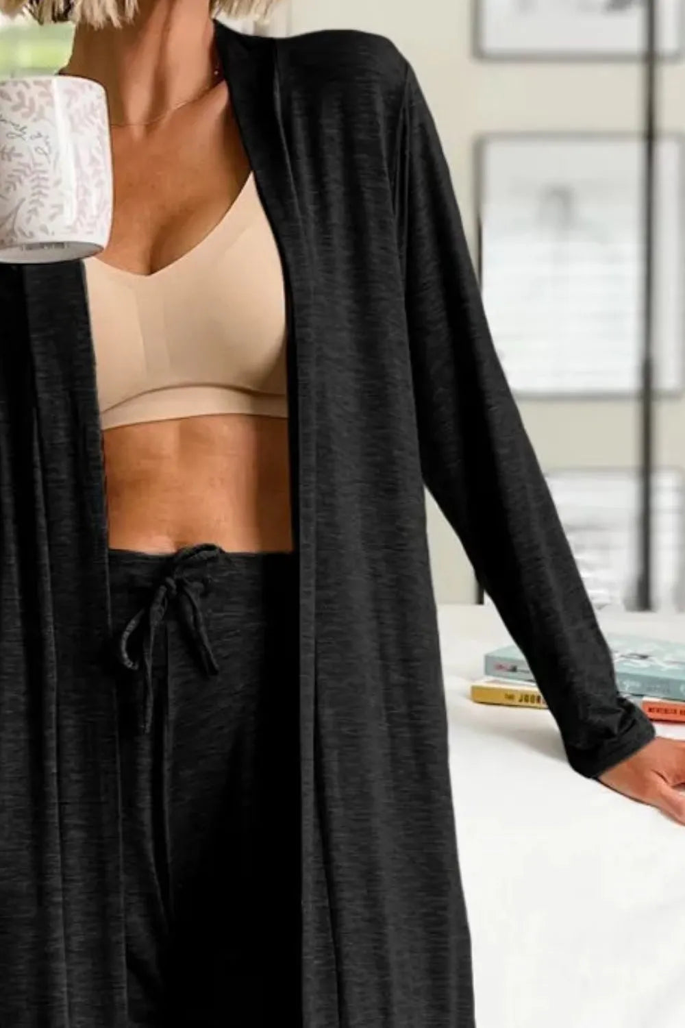 Close view of black open-front cardigan worn over a tan cropped top