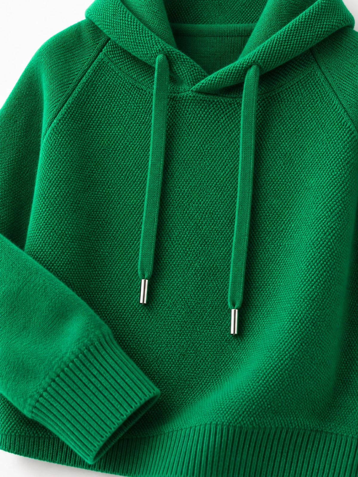 Emerald green sweater detail showing its hood opening, drawstrings and ribbed cuff.