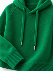 Emerald green sweater detail showing its hood opening, drawstrings and ribbed cuff.