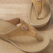 Close-up of tan toe-post sandal showing perforated strap and stitched footbed