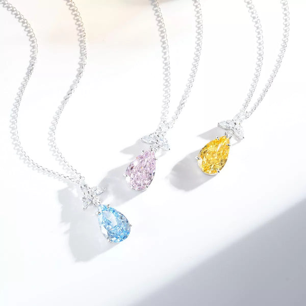 Three teardrop zircon necklaces in pastel blue, blush pink and light yellow on a white display