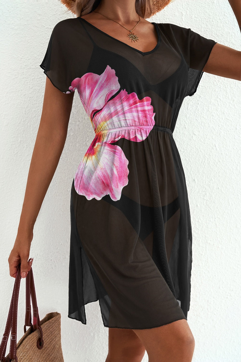 Model wearing black semi-sheer cover-up with pink floral print
