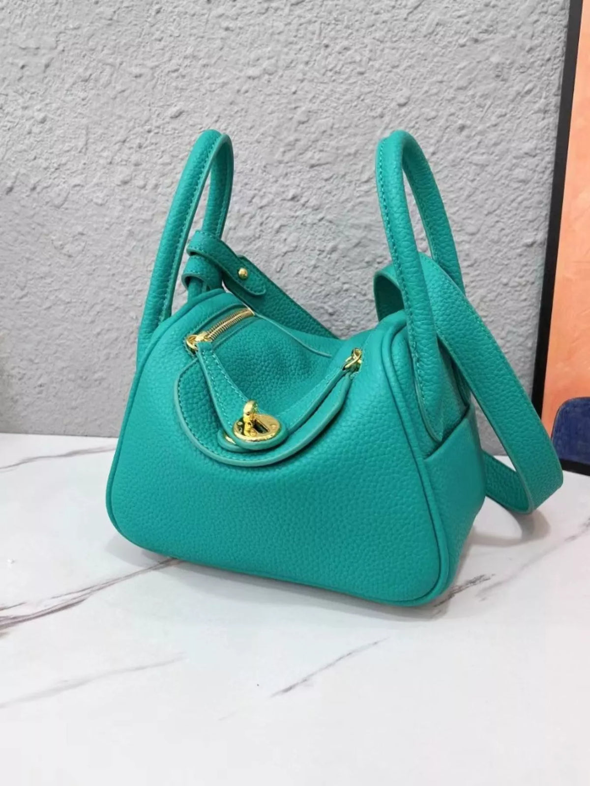 Teal pebbled crossbody bag angled to show its front flap and side