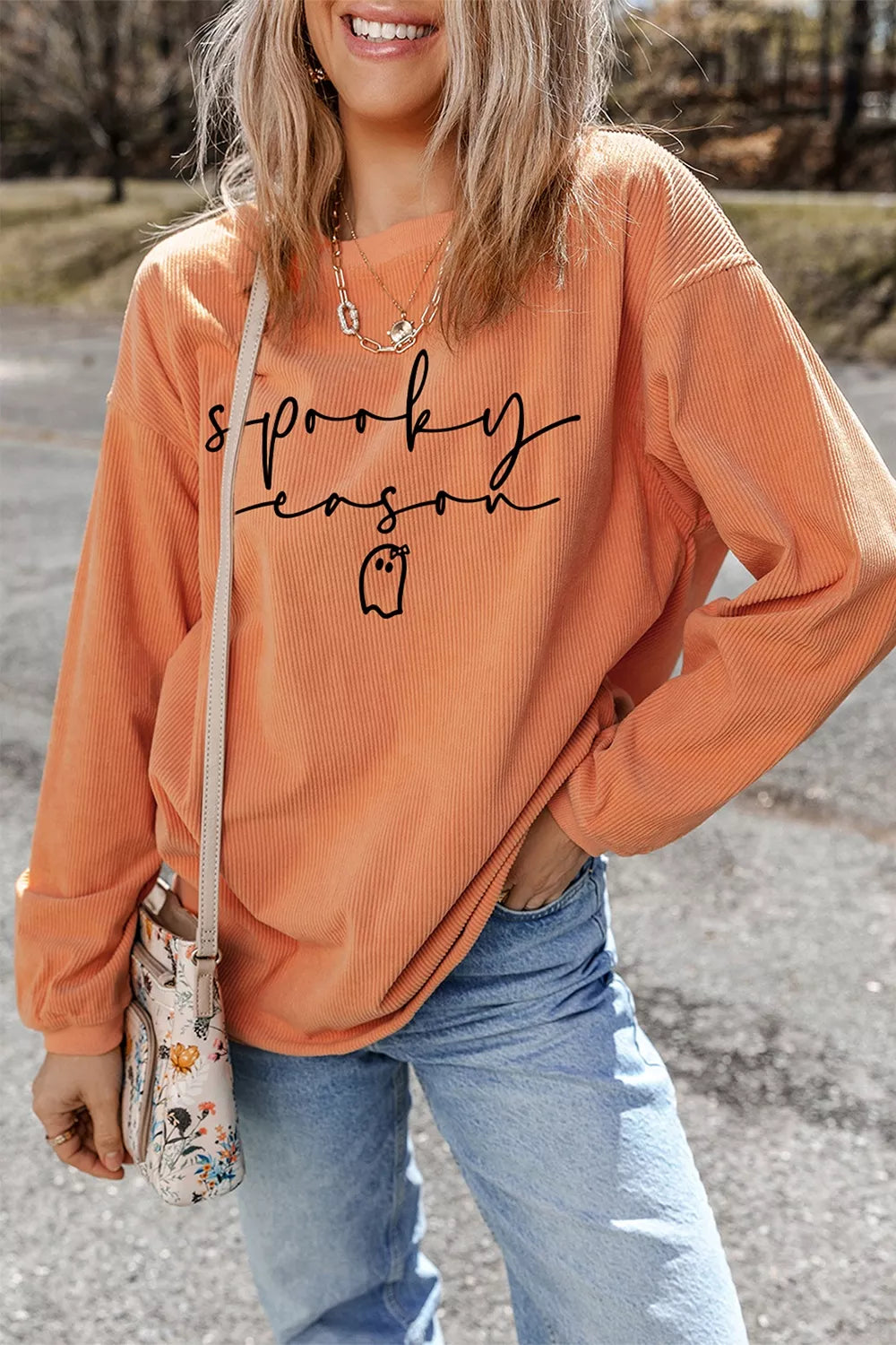 Front three-quarter view of orange spooky season ghost graphic pullover sweatshirt