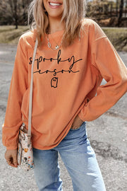 Front three-quarter view of orange spooky season ghost graphic pullover sweatshirt