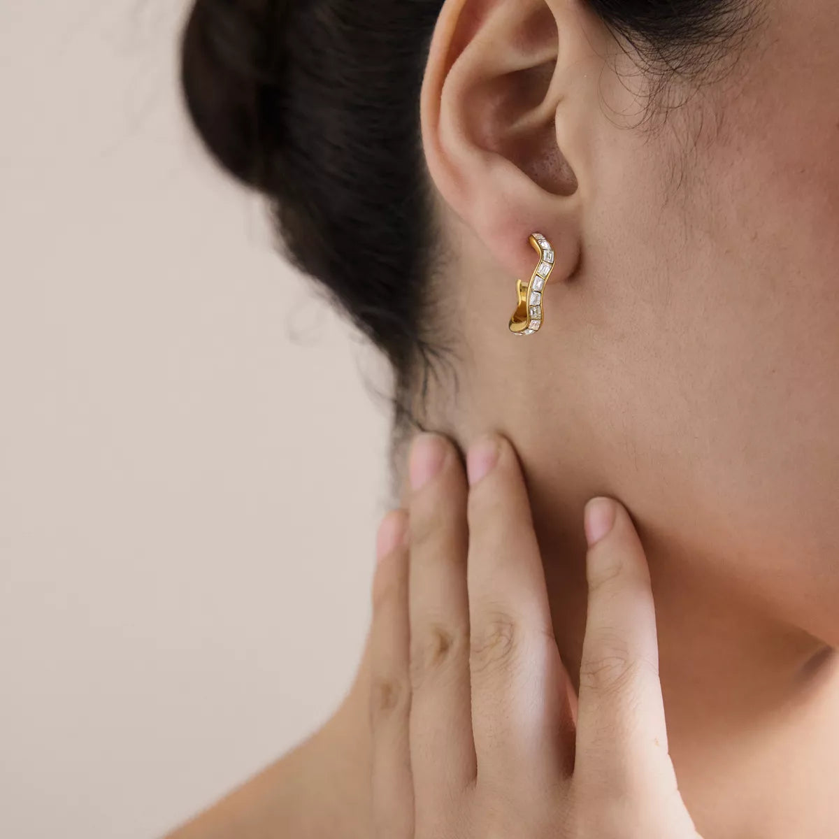 Gold-tone zircon hoop earring worn on an ear, viewed from the side