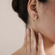Gold-tone zircon hoop earring worn on an ear, viewed from the side