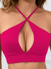 Hot pink halter crop cami with crossed neck straps and front cutout, worn view