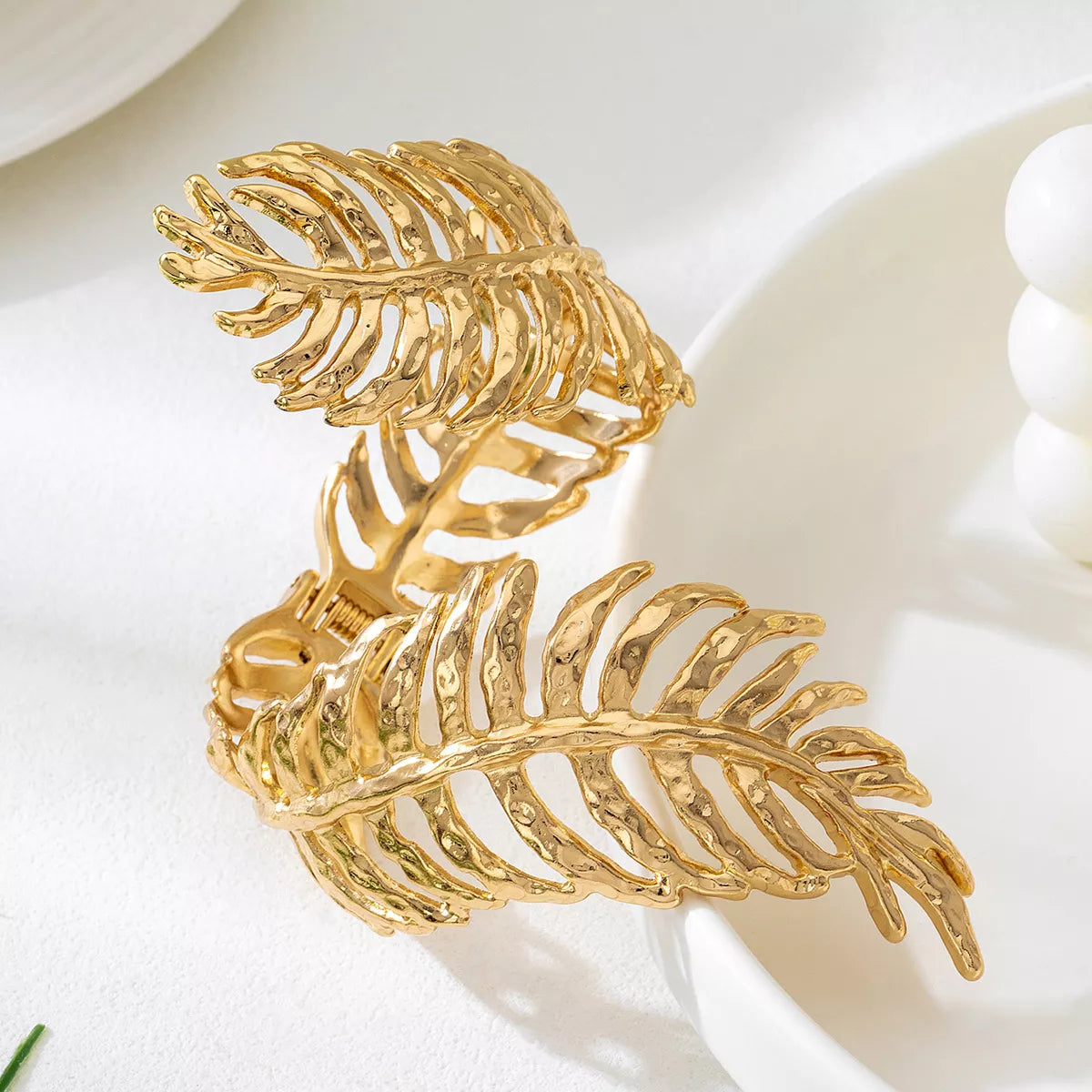 Close-up of sculpted gold-tone leaf cuff bracelet