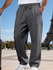 Front view of charcoal gray wide-leg drawstring pants beside a suitcase near the Eiffel Tower.