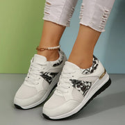 White sneakers with black floral panels worn from above