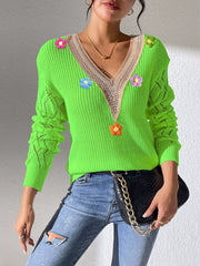 Bright green V-neck floral-appliqué sweater styled with jeans and a black bag.
