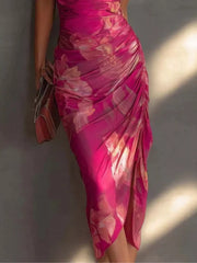 Close view of the pink floral midi dress showing diagonal ruching and the front skirt slit.