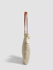 Side profile of the ivory crochet tote showing its narrow crocheted gusset and paired handles.