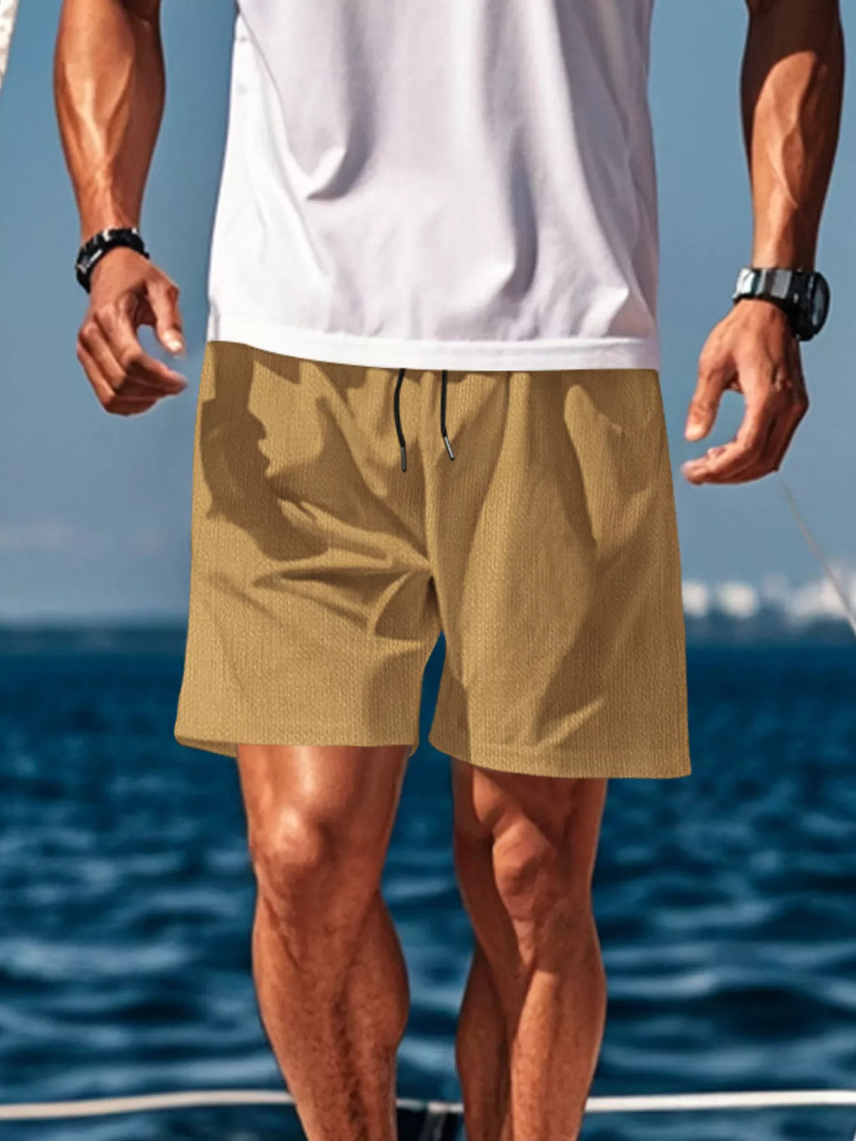 Man wearing mustard drawstring shorts by the water