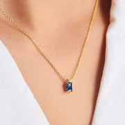 Dark blue rectangular pendant necklace worn with an open white shirt