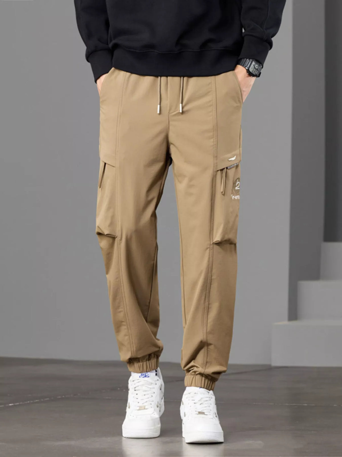 Front view of tan cargo joggers with drawstring waist, flap pockets and elastic cuffs.