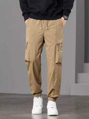Front view of tan cargo joggers with drawstring waist, flap pockets and elastic cuffs.