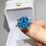 Blue-green ring held close-up in front of white jewellery box