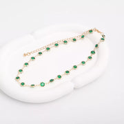 Dark green rhinestone choker with gold-tone setting, laid out on a white surface
