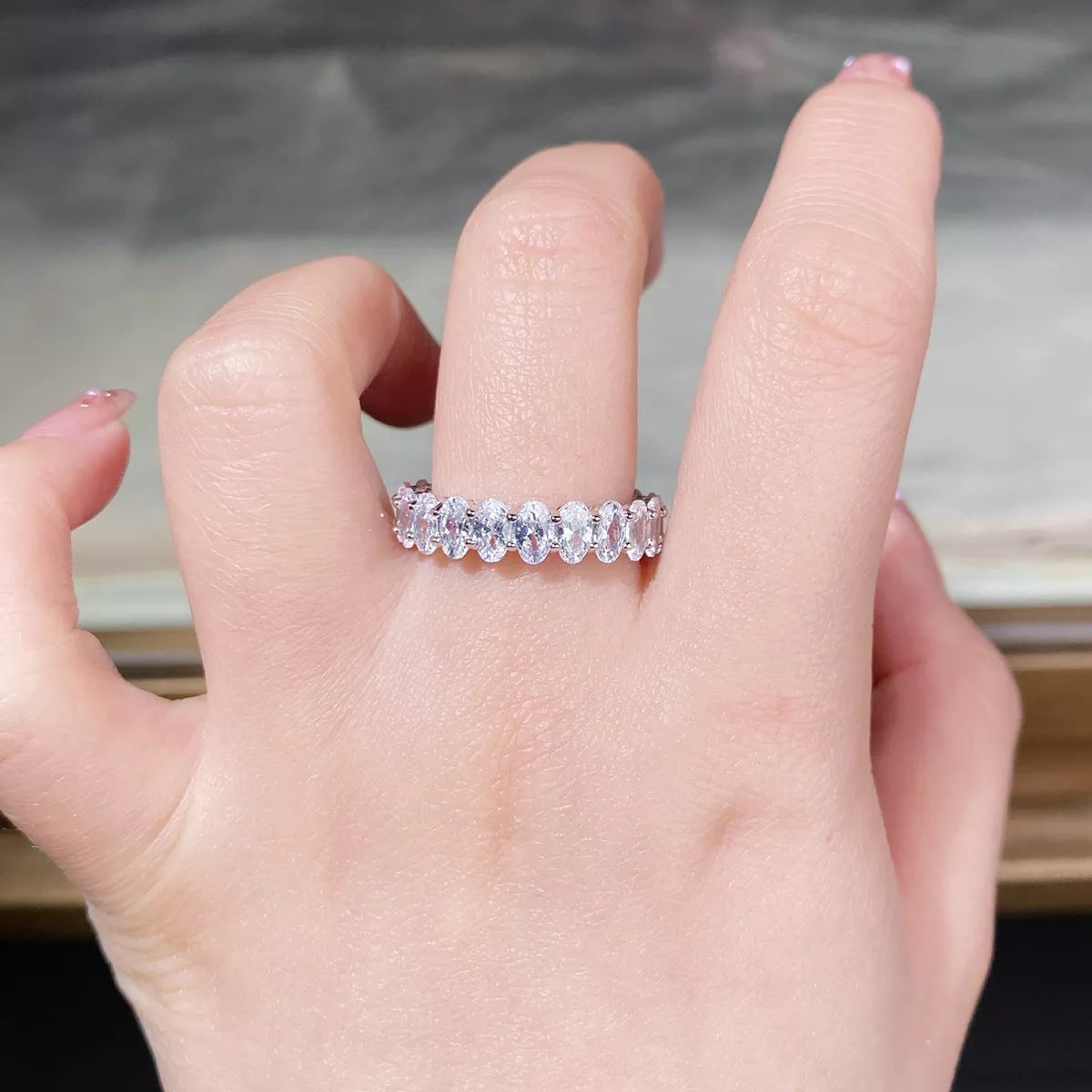 Clear stone silver band worn on a hand.