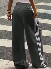 Back view of charcoal track pants with white side stripes