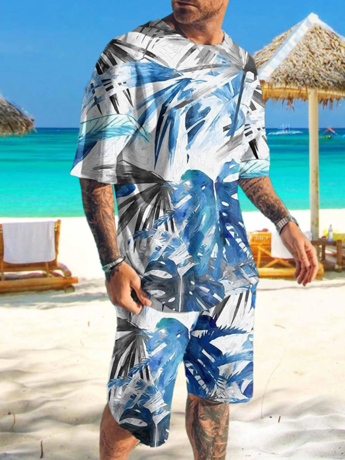 Man wearing white shirt and shorts with blue and black abstract print on a beach