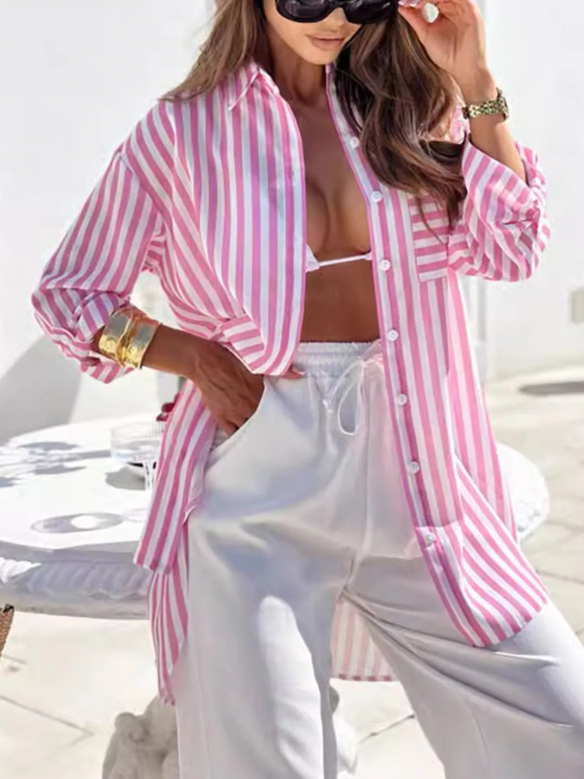 Model wearing pale pink and gray striped shirt dress with woven bag.