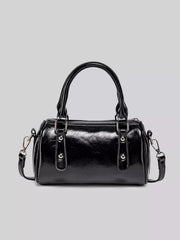 Front view of the glossy black Boston bag showing its two top handles and decorative front tabs.
