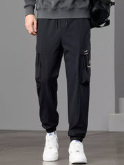 Front view of black cargo joggers styled with a gray sweatshirt and backpack.