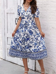 Front view of the blue and white floral V-neck midi dress, with the skirt held out at both sides.