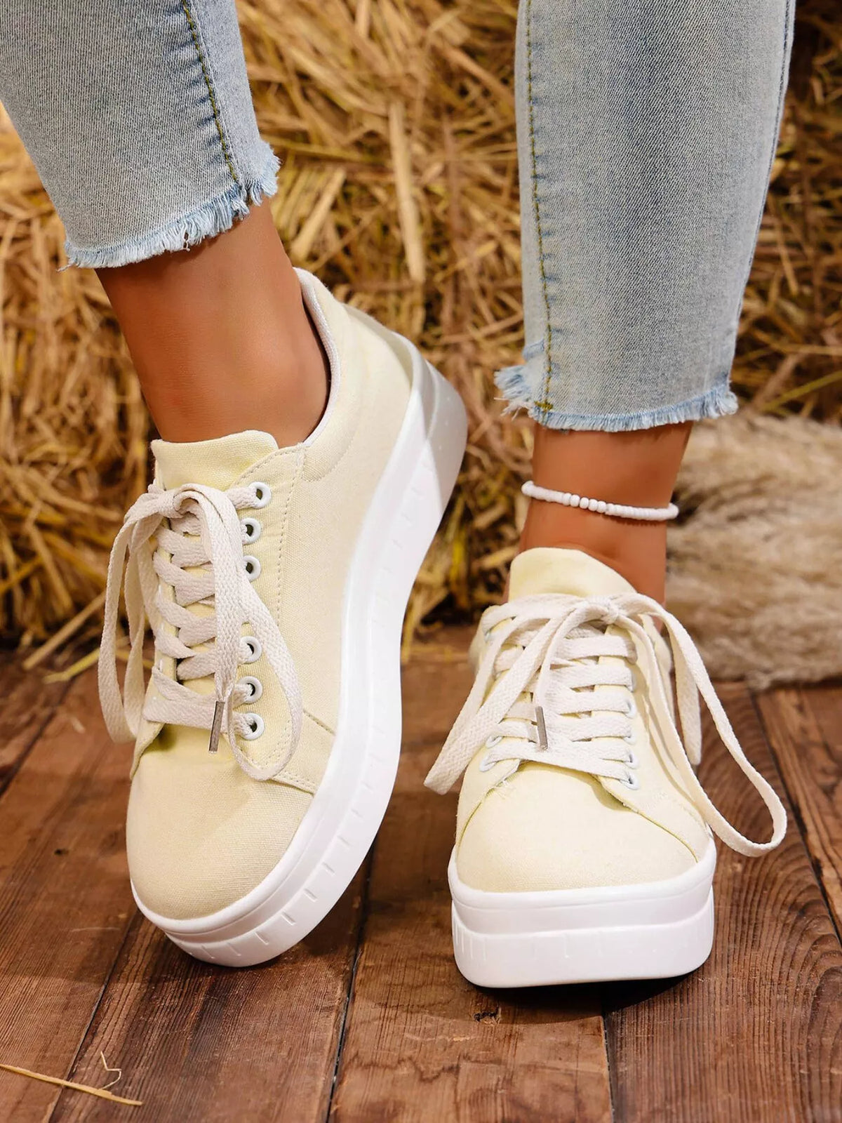 Pair of white lace-up platform sneakers worn with jeans