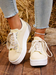 Pair of white lace-up platform sneakers worn with jeans