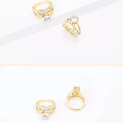 Gold-tone ring with a clear center stone displayed on a white background