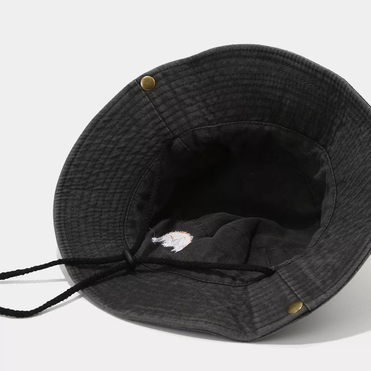 Inside of black mountain-embroidered bucket hat showing chin cord and eyelets
