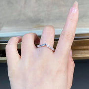 Silver-tone V-shaped ring with small clear stones worn on a finger.