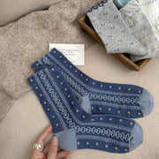 Blue patterned knit socks laid out on a blanket