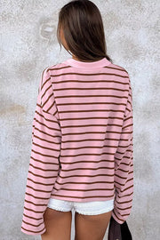 Back view of oversized pink striped long-sleeve shirt worn with white shorts.
