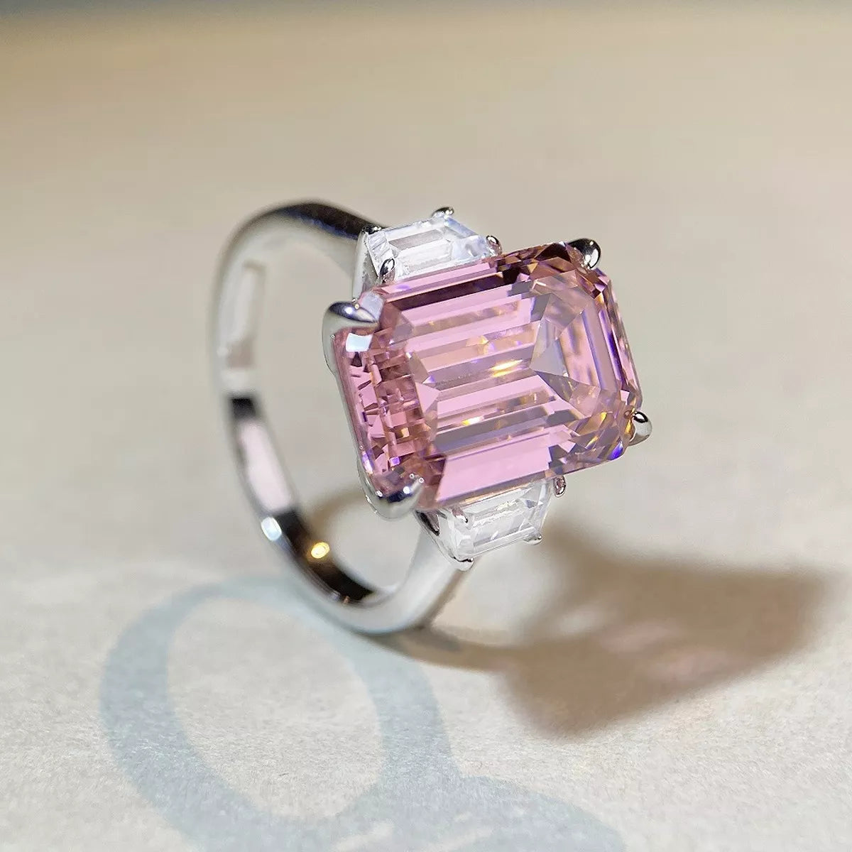 Angled view of the pink rectangular gemstone ring with clear side stones and a silver-tone band