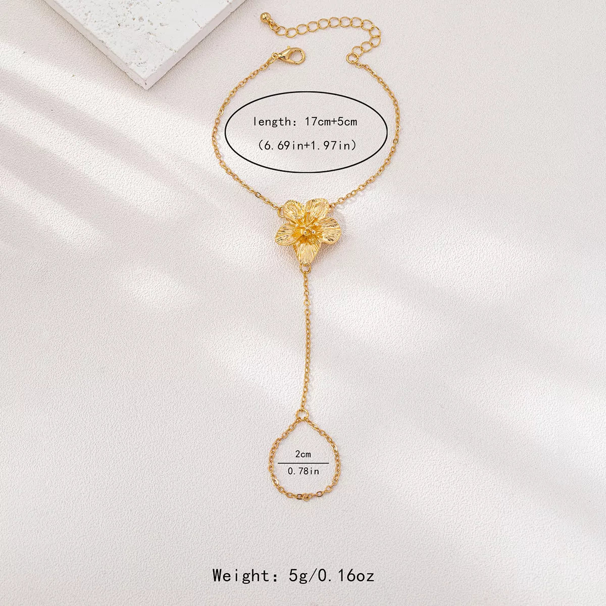 Gold-tone flower hand chain bracelet with size information in image