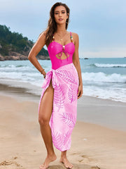 Hot pink cutout swimsuit with matching pink leaf-print sarong, full-length view