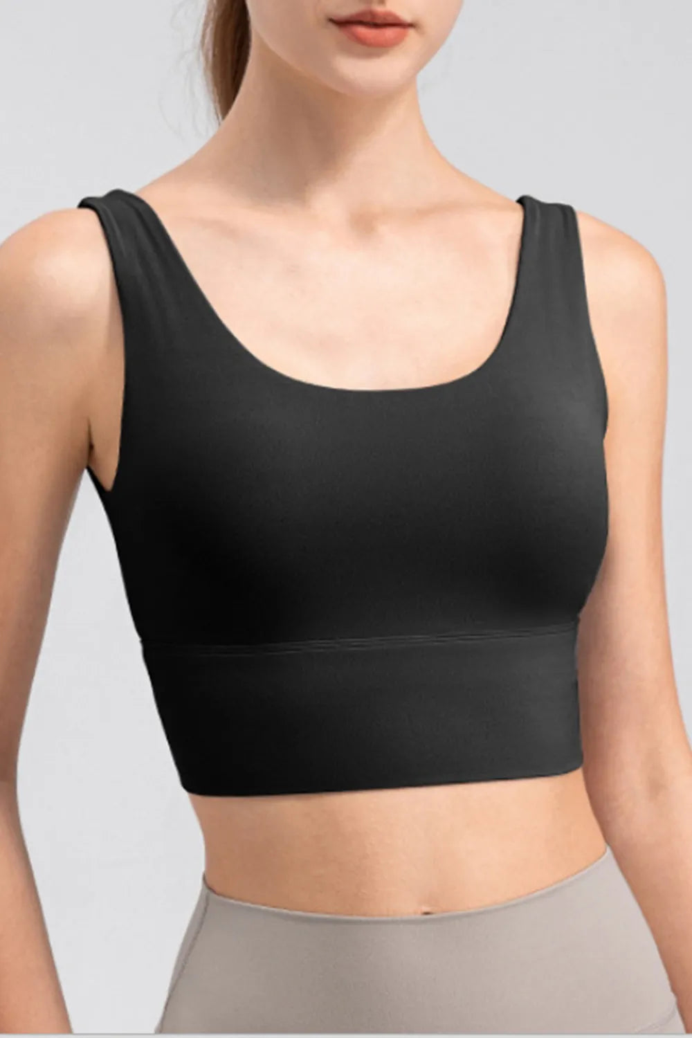 Close-up of black scoop-neck cropped tank showing wide straps and the broad stitched underbust band