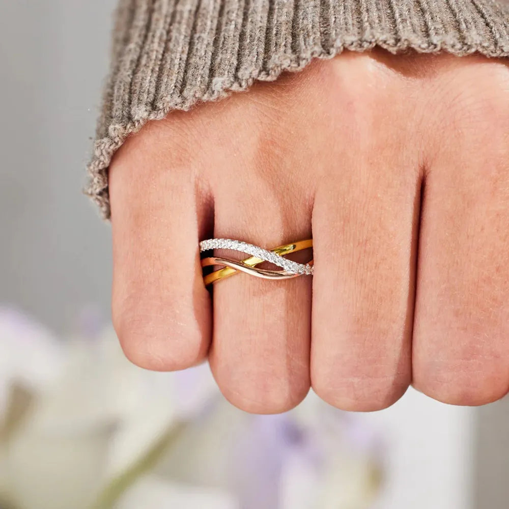 Close view of the crossed gold and silver-tone ring bands worn on a hand