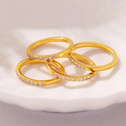 Three gold-tone zircon rings arranged together on a white surface