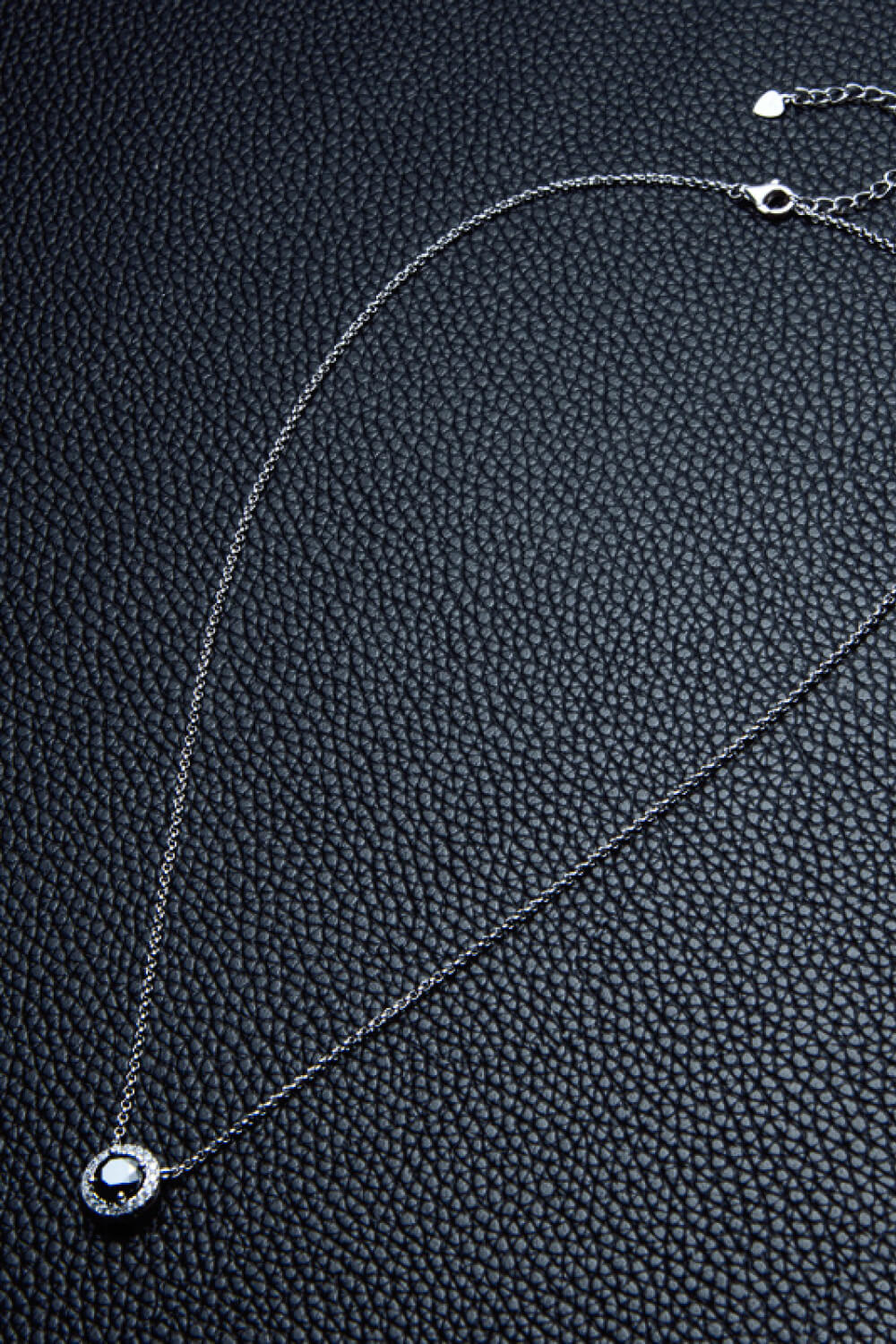 Fine necklace chain laid out on a dark textured surface